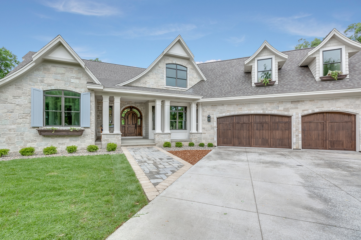 Elegant modern stone house with arched doorway and wooden garage doors