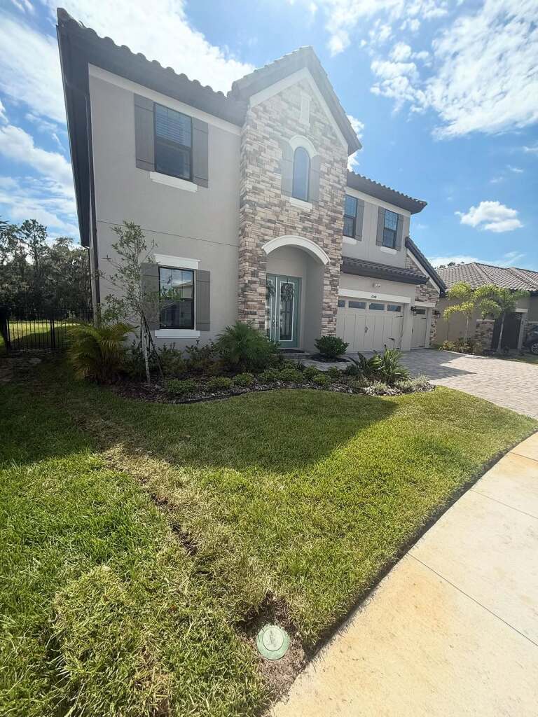 Modern two-story house with stone facade and lush green lawn