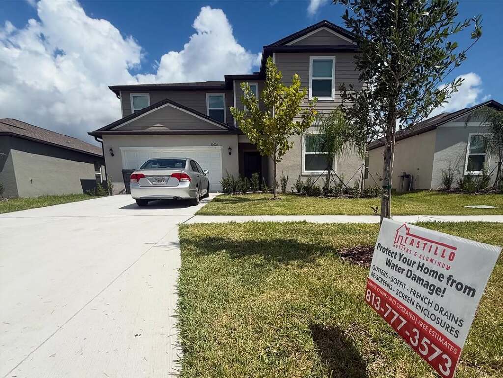 Suburban house with car and water damage prevention sign