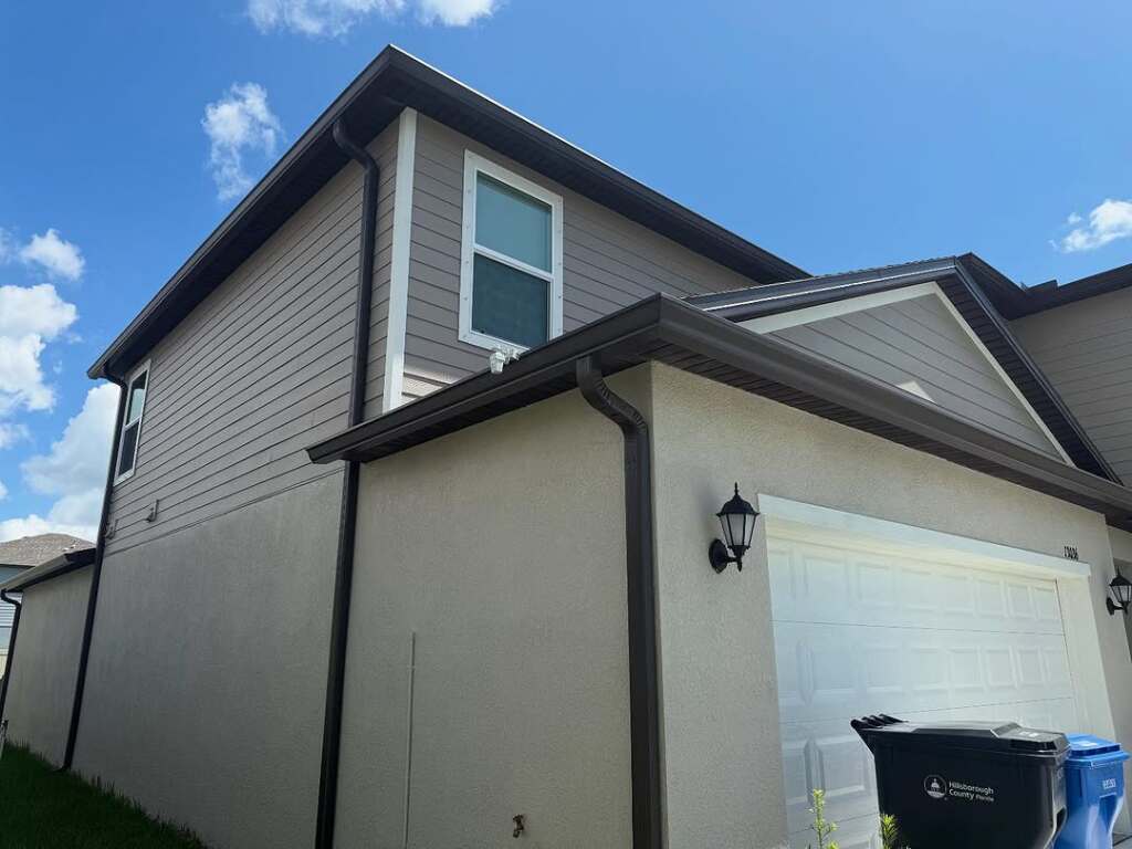 Modern two-story house with light siding and garage under a blue sky