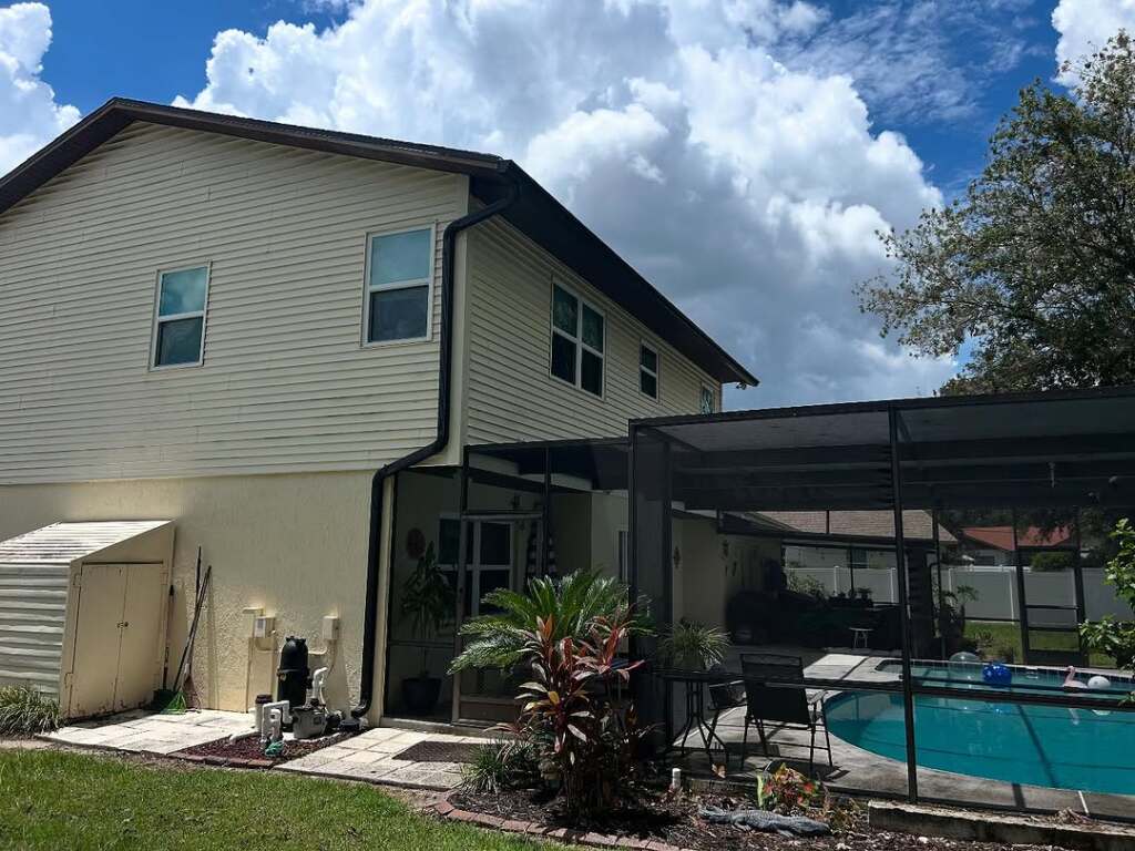 Modern suburban house with patio and pool on a sunny day.