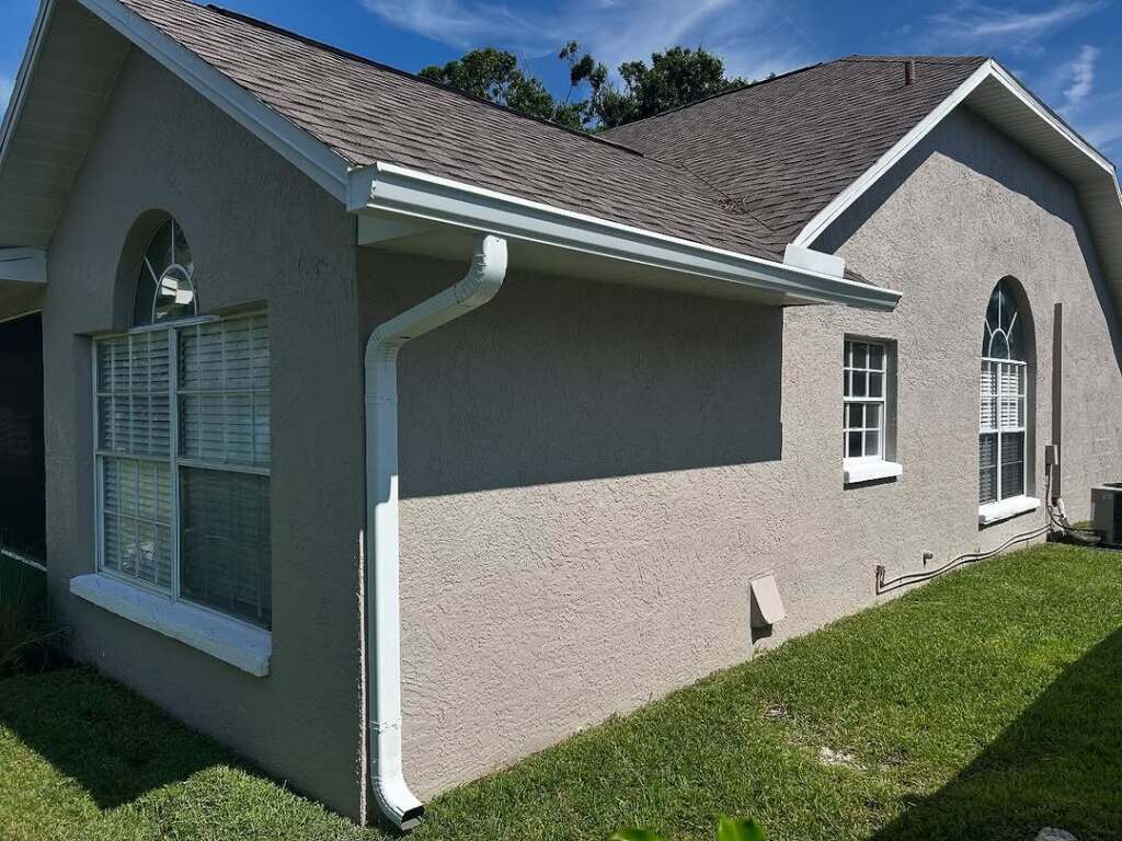 Side view of a residential home with light beige walls and arched windows