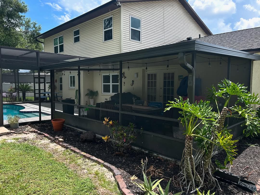 Backyard view of a house with screened patio and swimming pool