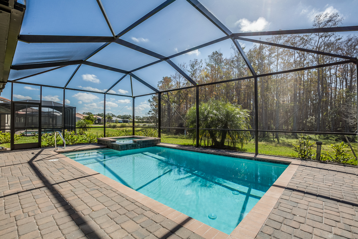 Screen-enclosed pool with hot tub and scenic nature view