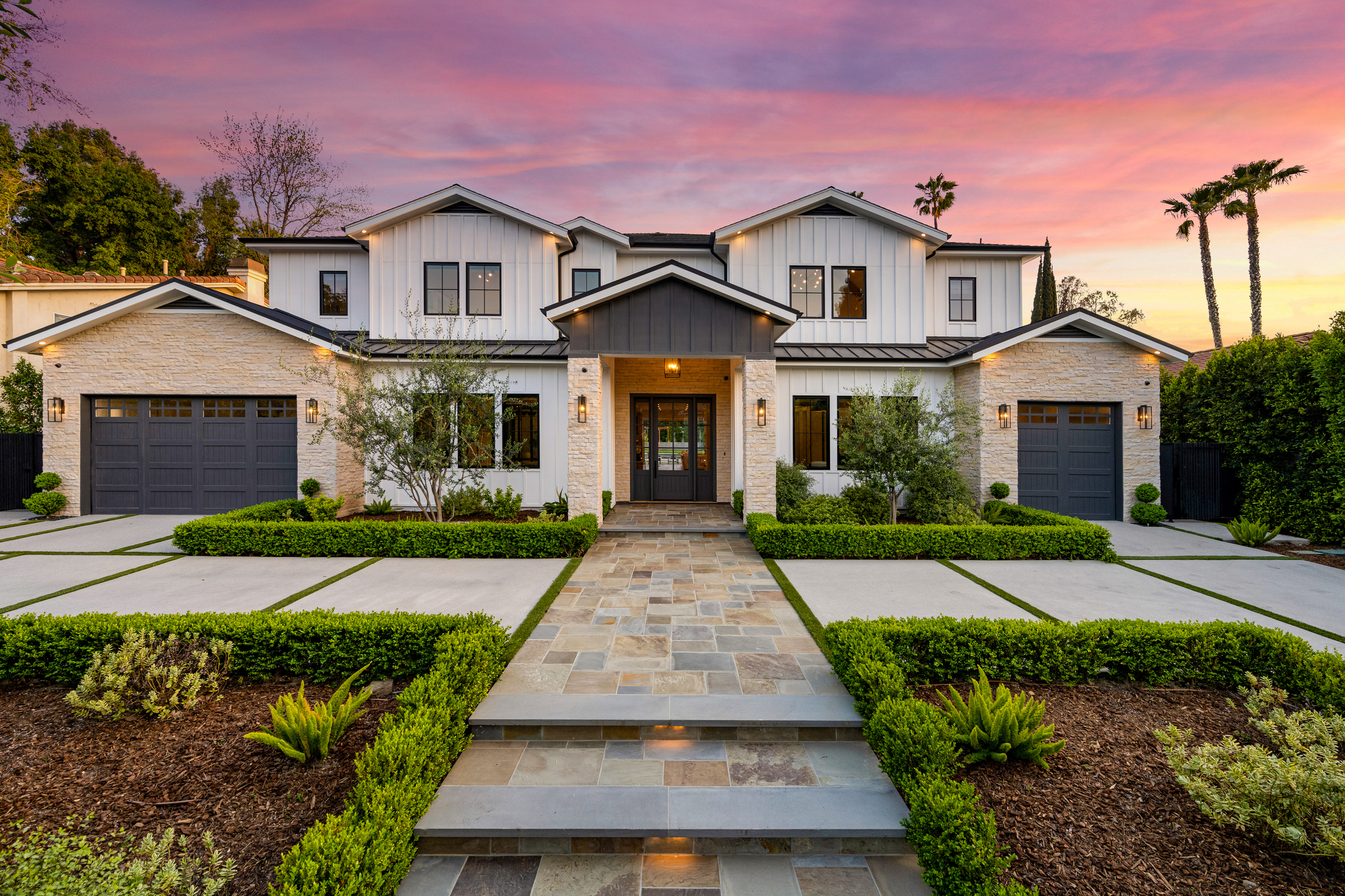 Modern luxury home exterior with manicured landscape at sunset
