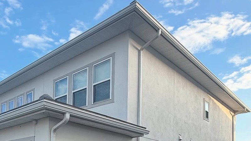 Modern two-story house with white stucco exterior and large windows.