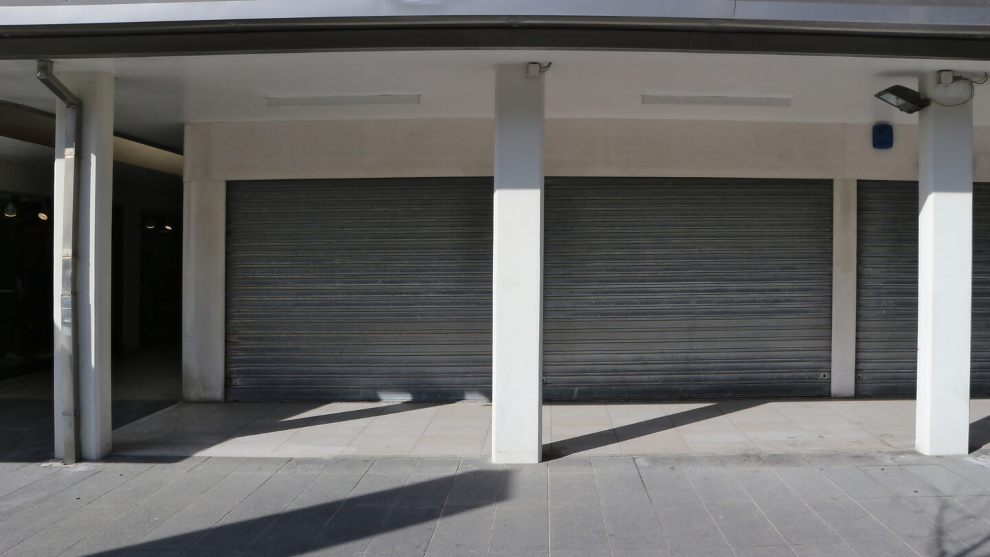 Closed gray garage doors with shadows on pavement