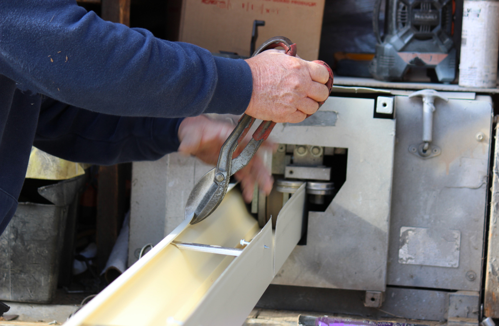 Person cutting metal sheet with snips in a workshop setting
