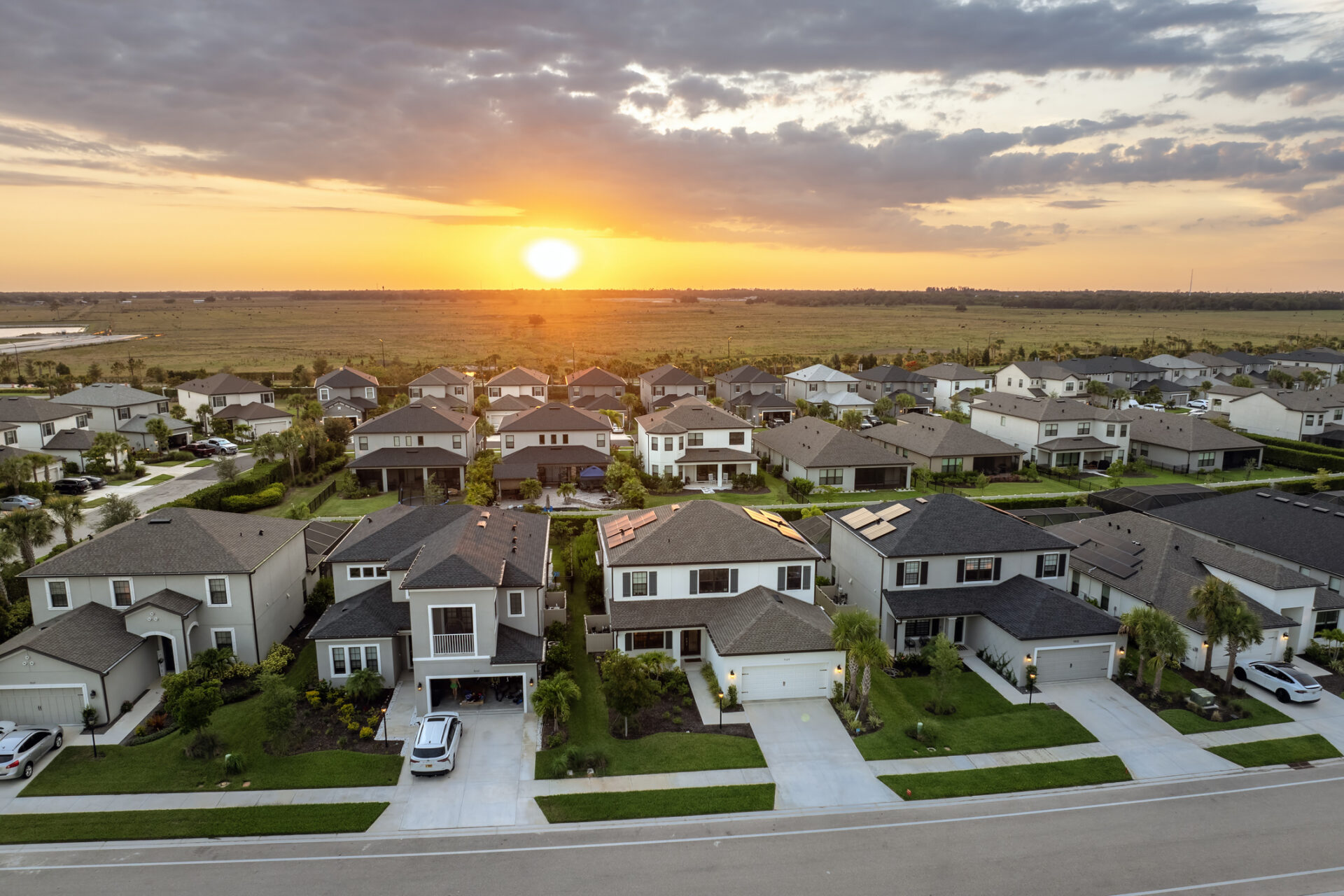 Aerial view of suburban neighborhood at sunset with modern homes