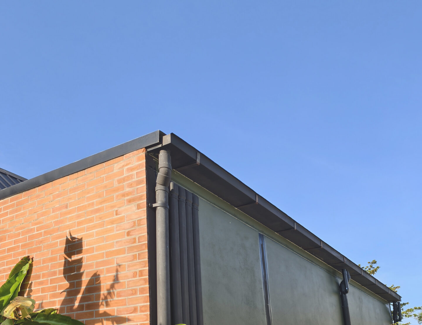 Modern building corner with red brick and blue sky background.