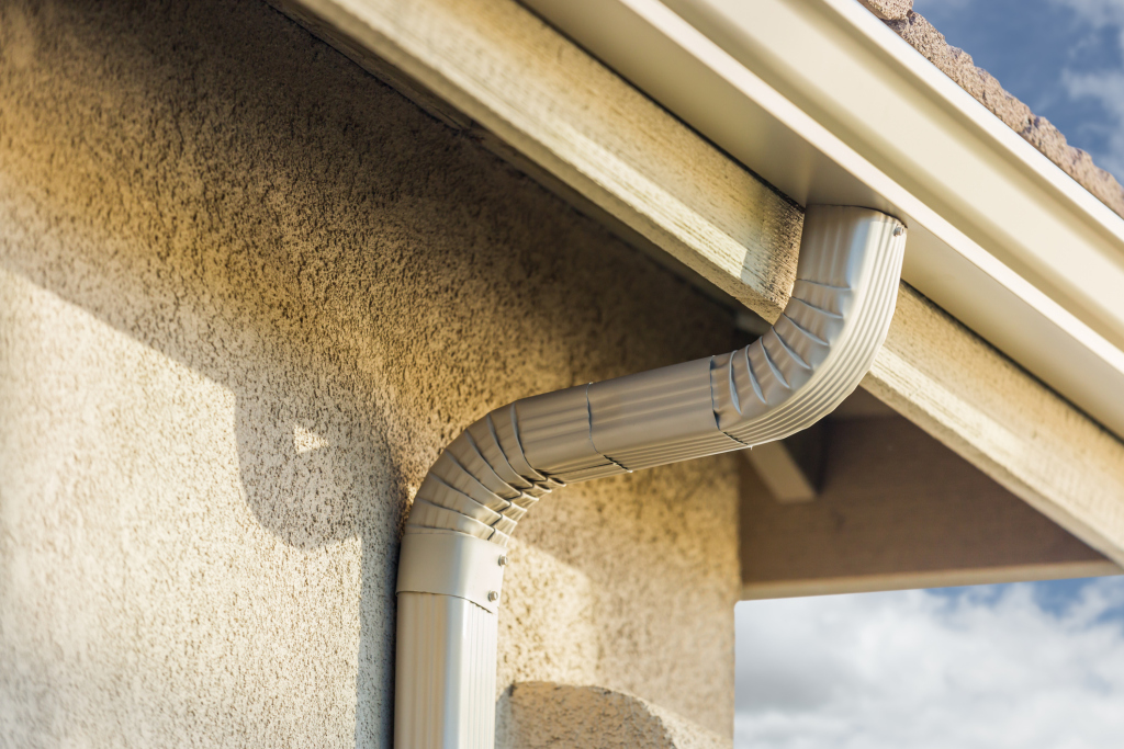 House gutter system with downspout on wall