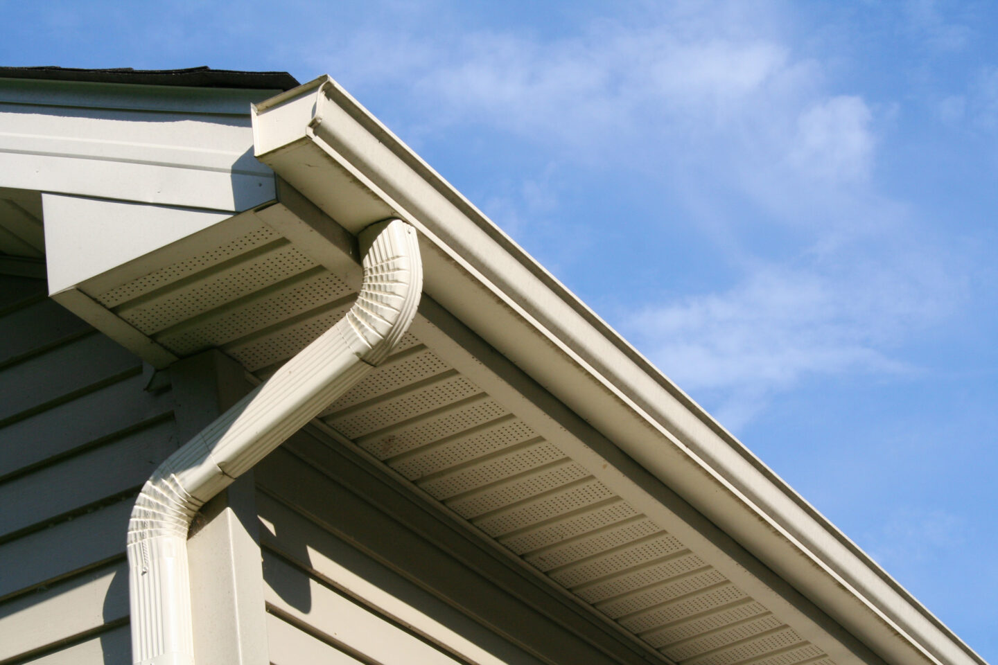 House gutter system against a clear blue sky, focusing on drainage pipes