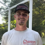 Man in branded shirt and cap standing under a screen enclosure.