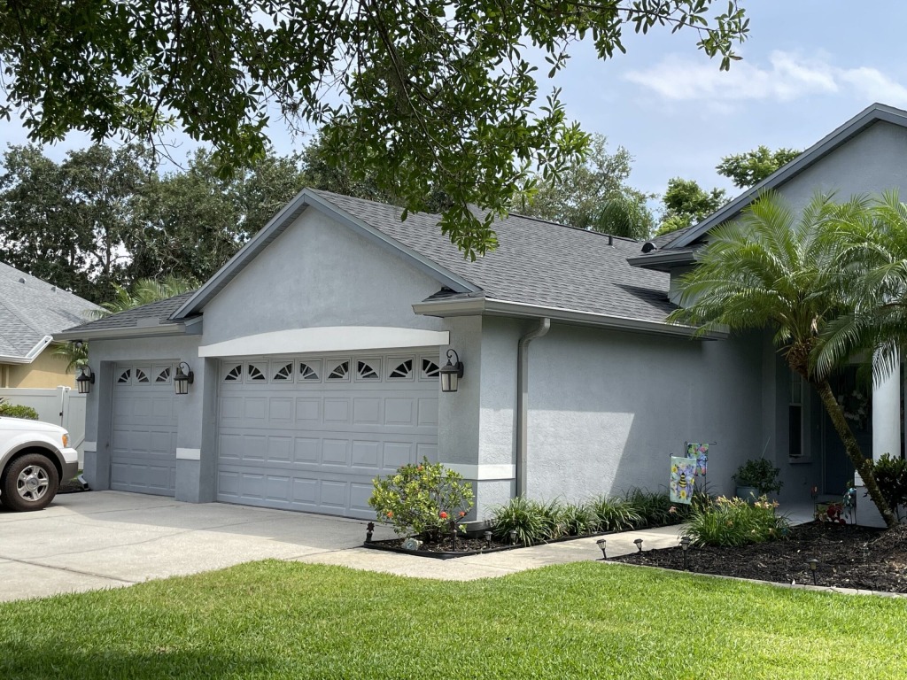 Suburban home with well-kept garden and palm tree, showcasing double garage.